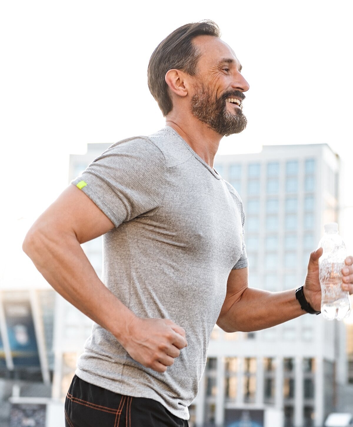 Man jogging with water bottle outdoors.
