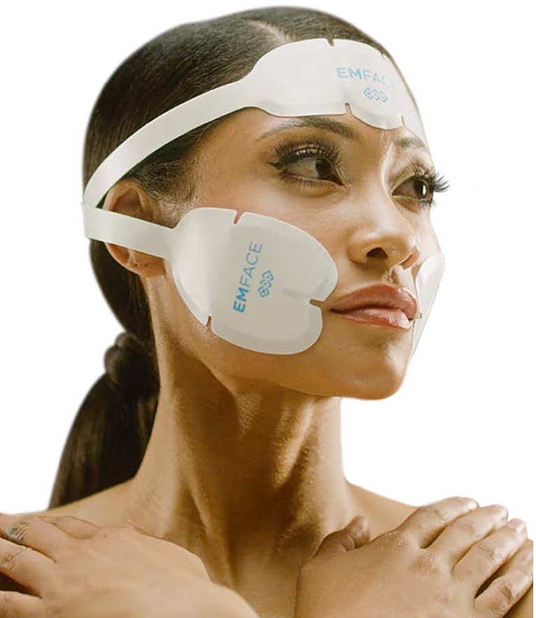 Woman using EMFACE facial treatment device.