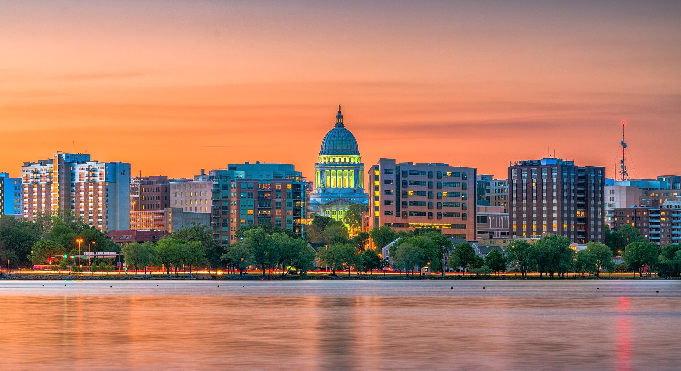 Sunset over city skyline with domed building.