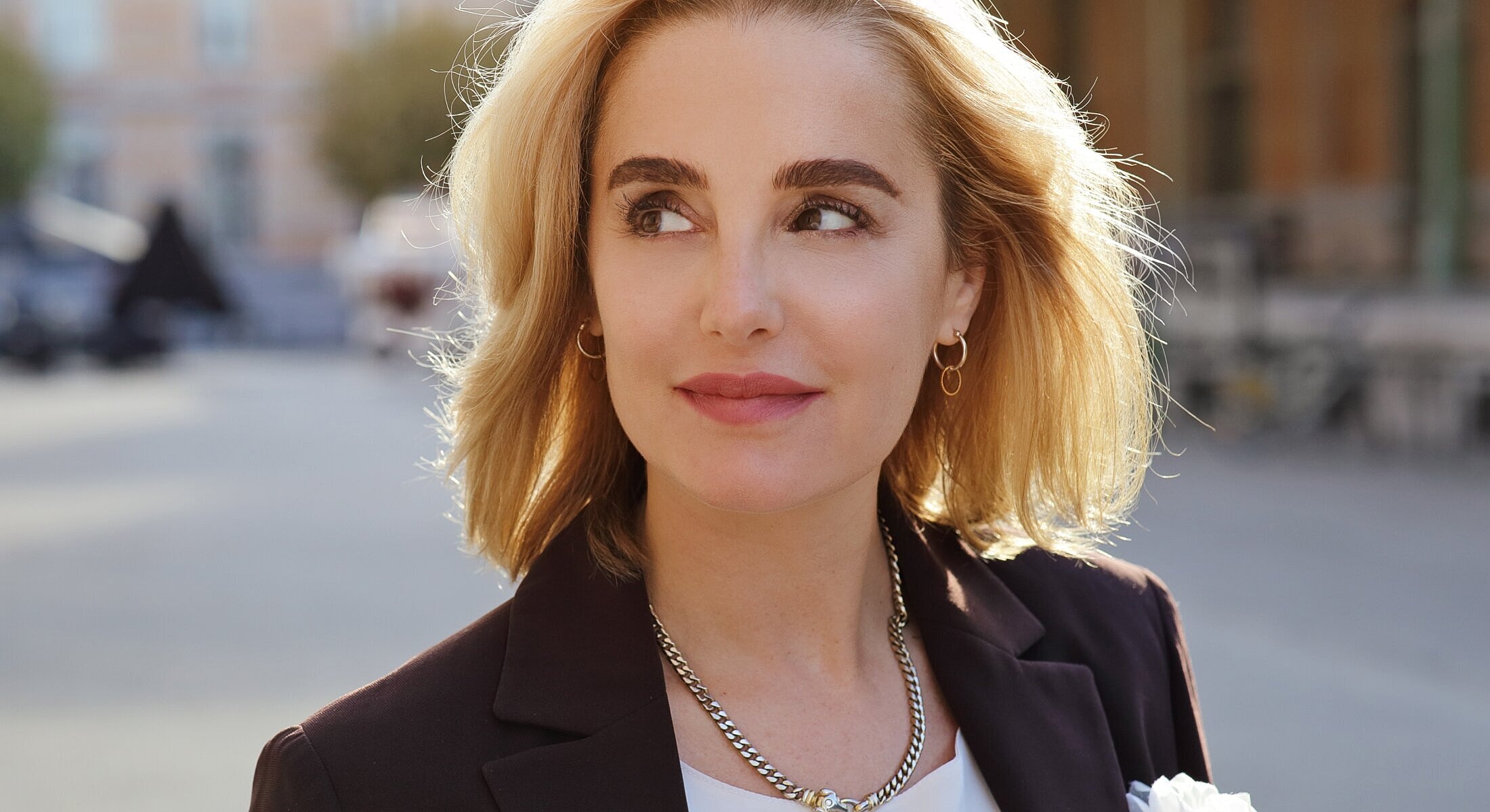 Woman with blonde hair, wearing a stylish outfit.