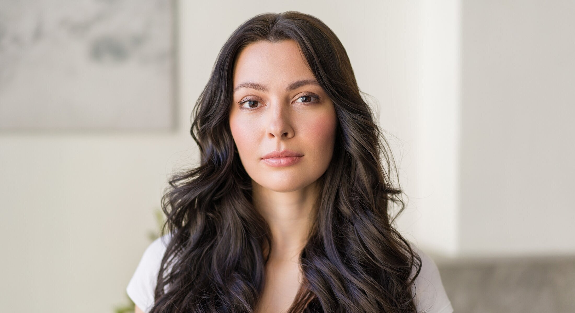 Woman with long wavy hair, natural makeup.