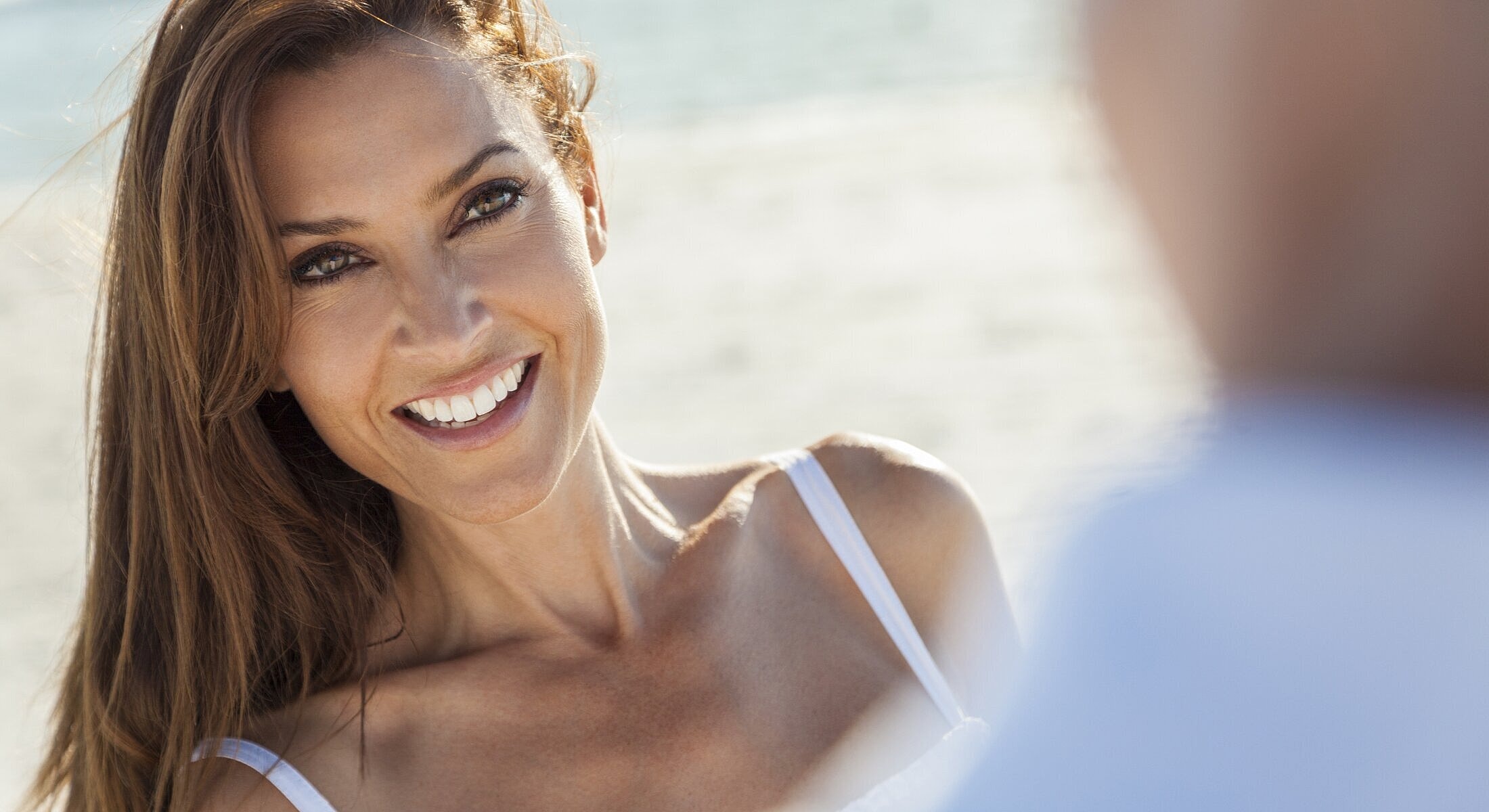 Smiling woman enjoying a sunny beach day.